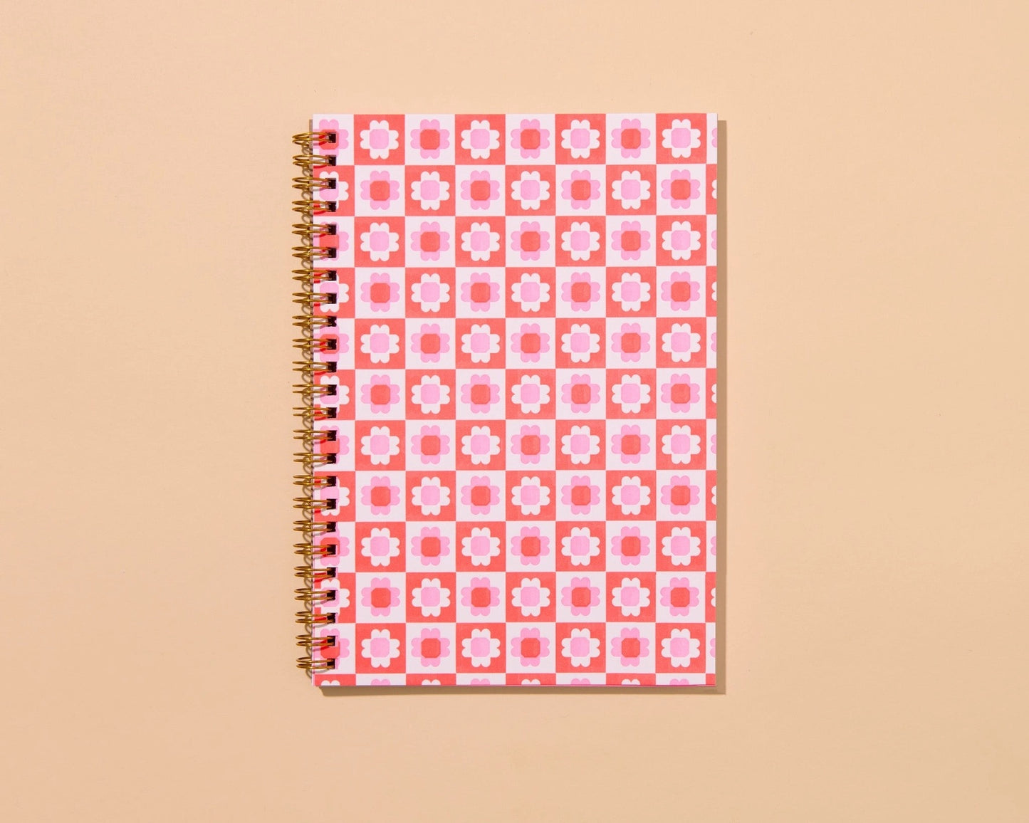 Front cover of a spiral notebook. Notebook is letterpress printed with a pink and purple floral quilt print. 