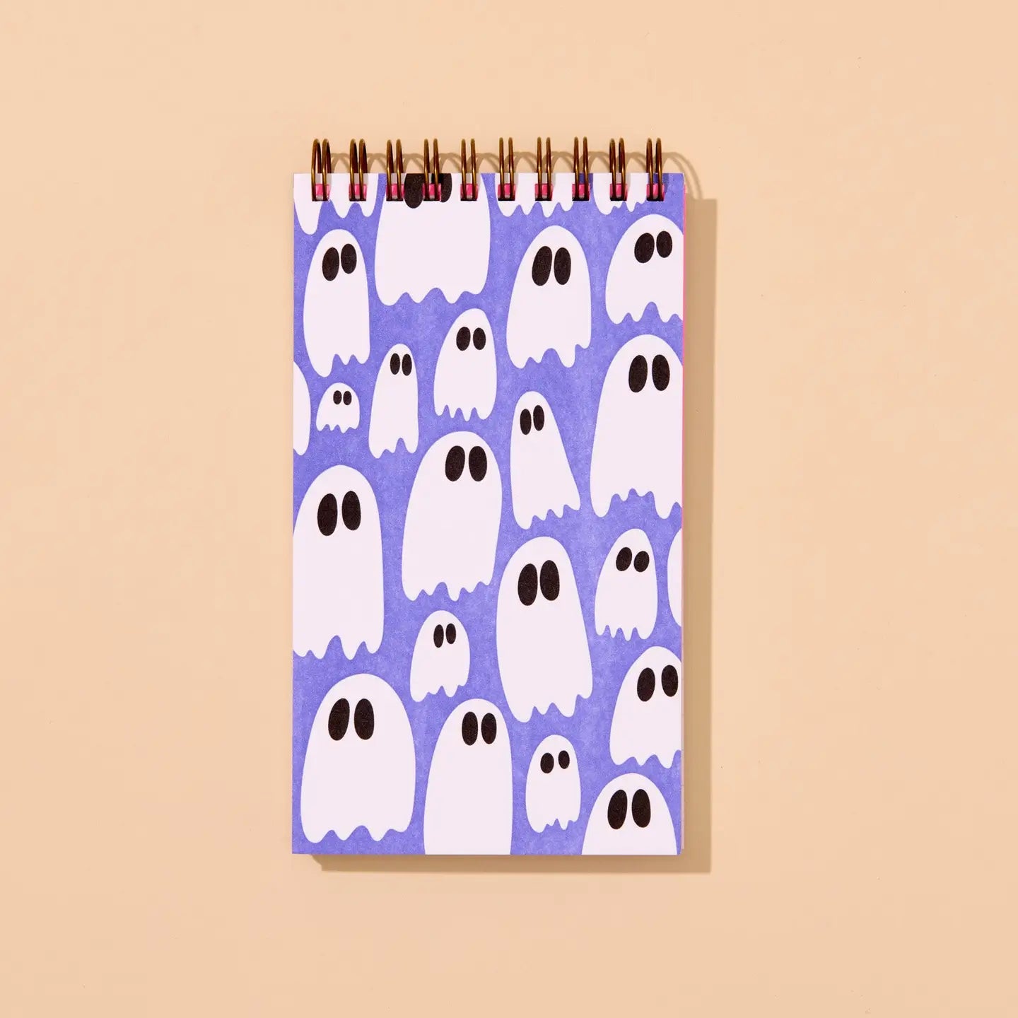 Top spiral purple notebook with ghost pattern on a beige background