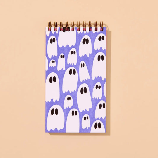 Top spiral purple notebook with ghost pattern on a beige background