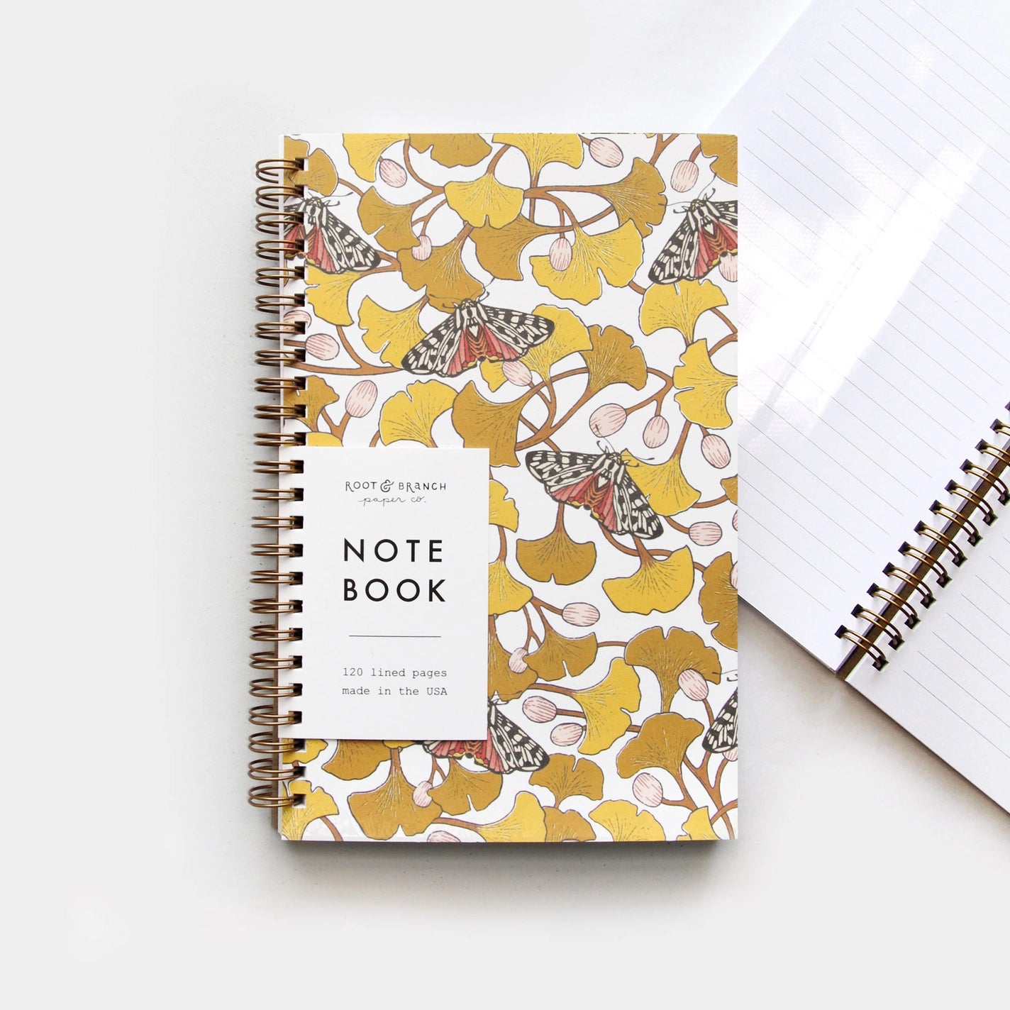 Front cover of a notebook featuring a ginkgo and tiger moth design 