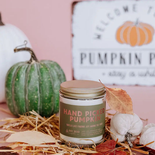 Candle labeled 'Hand Picked Pumpkin' with pumpkins and fall decor in the background