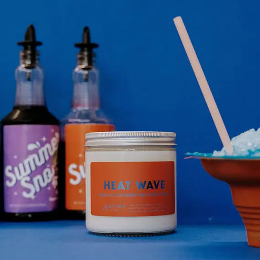 Candle jar with orange label: heat wave. Summer snow cone decor in background 
