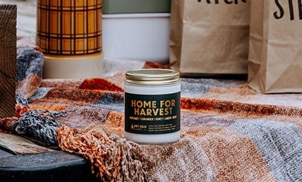 Jar candle labeled Home for Harvest on a blanket 