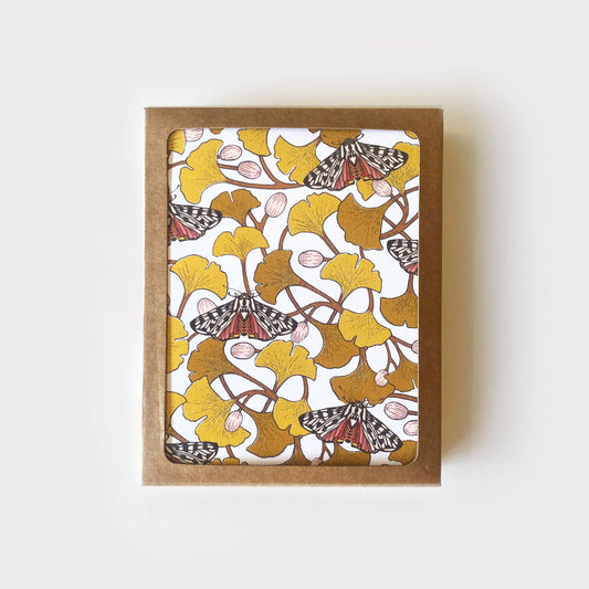 Brown Kraft box holding boxed set of greeting cards. Cards are illustrated with yellow ginkgo leaves and moths. 