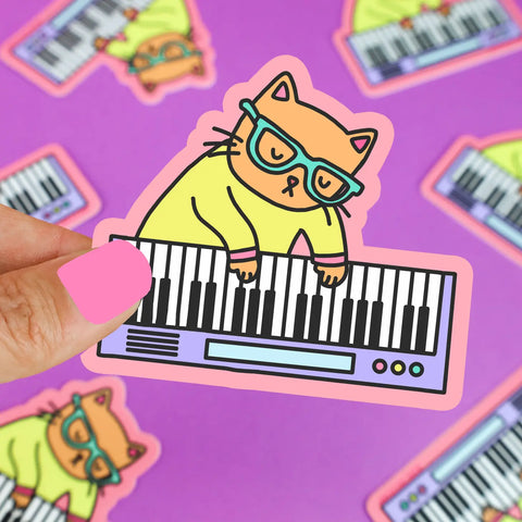 Orange cat with blue glasses and a yellow shirt playing a keyboard