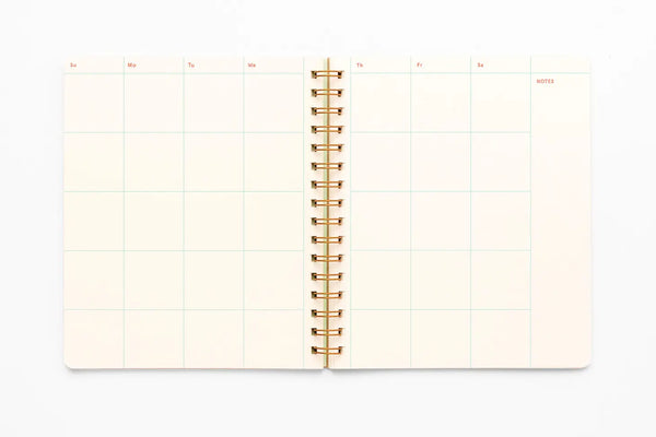 Inside monthly view of planner. Spiral bound. White pages with blue lines and red text heading for the days of the week. 
