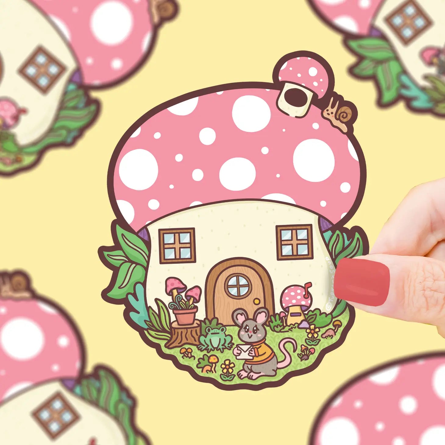 Die-cut sticker of a mushroom cottage with a mouse holding an envelope outside. Colors are pink, white, cream, brown, green, and grey