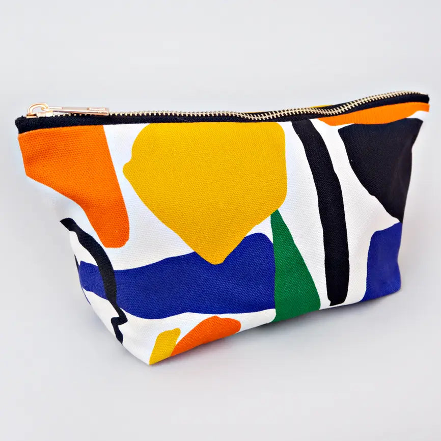 White bag with orange, yellow, blue, black, and green shapes. Brass zip at top. 