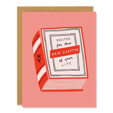 Peach card with an illustration of a red book. The cover of the book has black text reading "excited for this new chapter of your life." Inside of card is white.