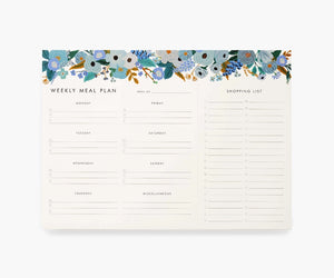 White notepad with blue flowers at the top. Black text reads "weekly meal plan" and has lines for each day of the week. Black text reads "shopping list" with lines for items. 
