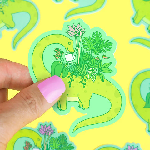 die-cut sticker in the shape of a dinosaur. Lime green sauropod dinosaur is watering plants on its back. 