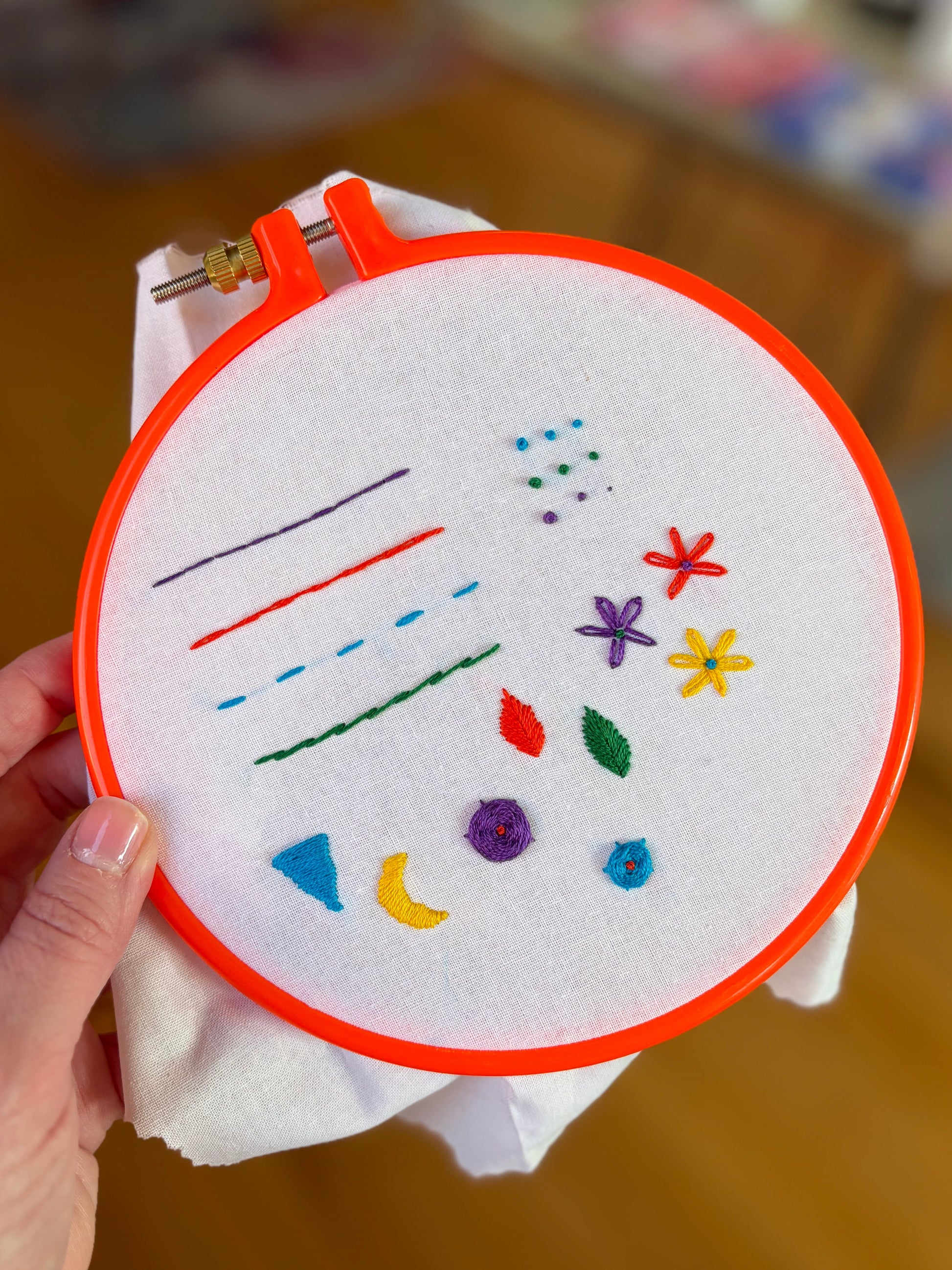 Embroidery hoop with colorful stitches on a wooden surface