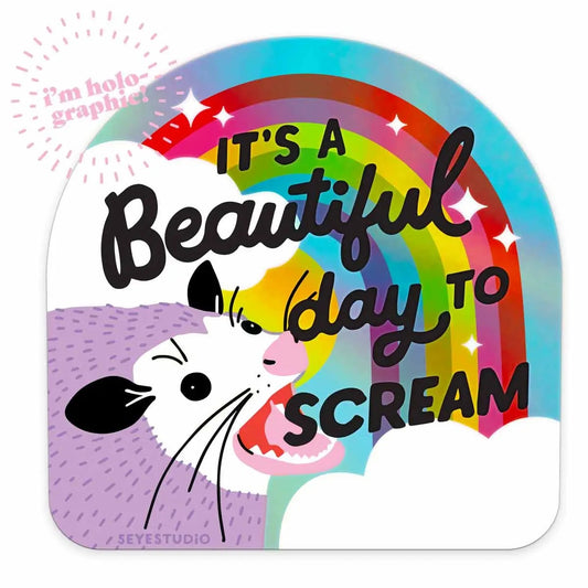 Holographic sticker with an opossum, rainbow, and text 'It's a Beautiful Day to Scream'