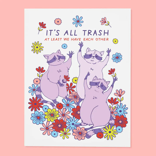 White greeting card featuring raccoon and flower illustrations. Text: it’s all trash. At least we have each other 