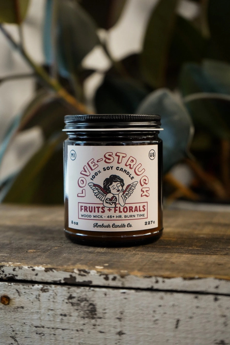 Amber jar candle. White label with red text reading "love struck, fruits and florals" 