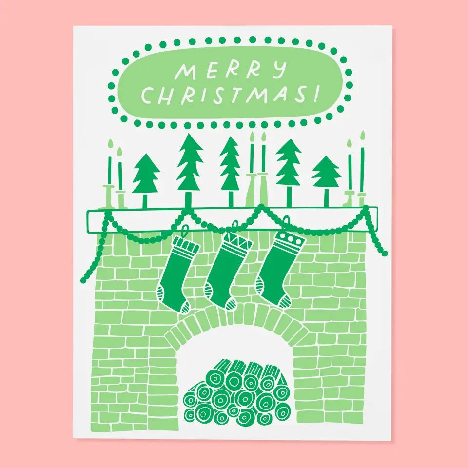 Greeting card with an illustration of a fireplace with stockings, trees, and 'Merry Christmas!' text on a pink background.