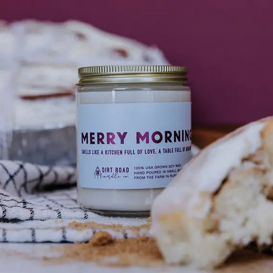 Candle jar labeled 'Merry Morning' with a blurred background of bread and kitchen items.