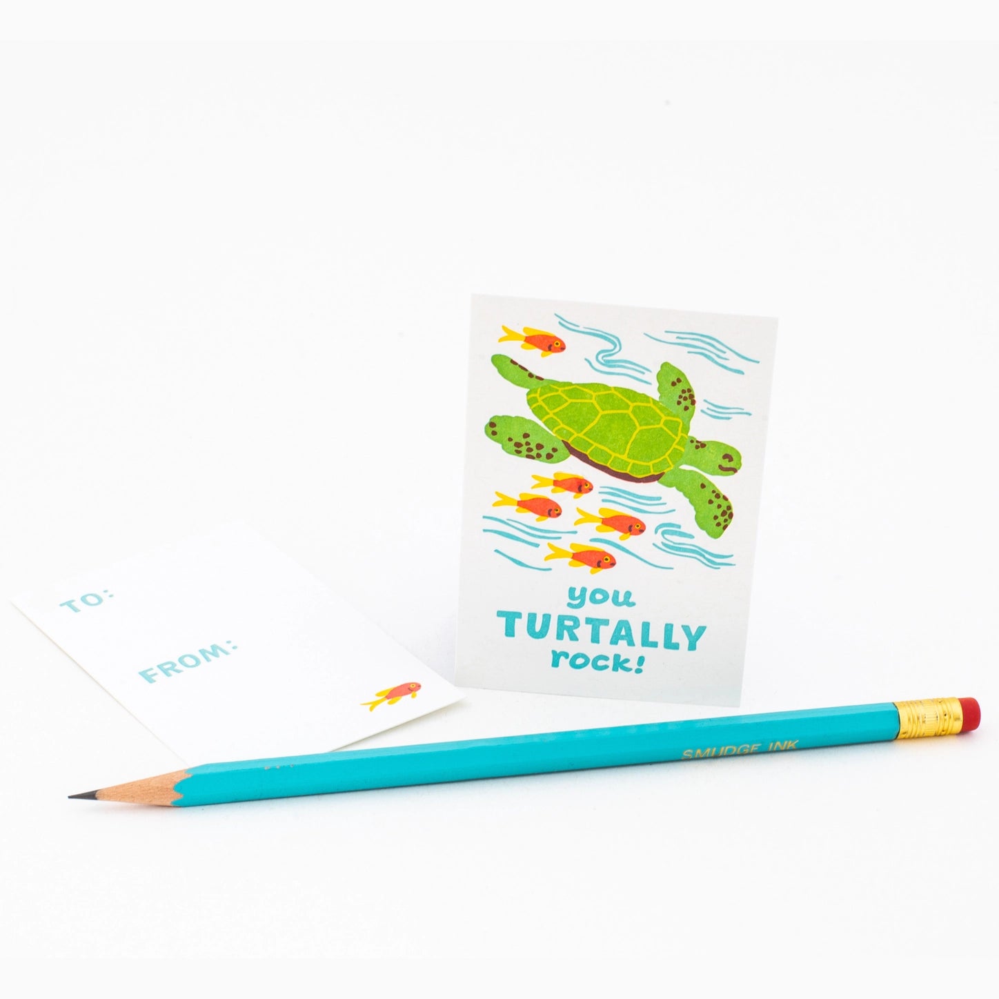 White valentine with an illustration of a turtle and blue text: you turtally rock. Blue pencil in foreground. 