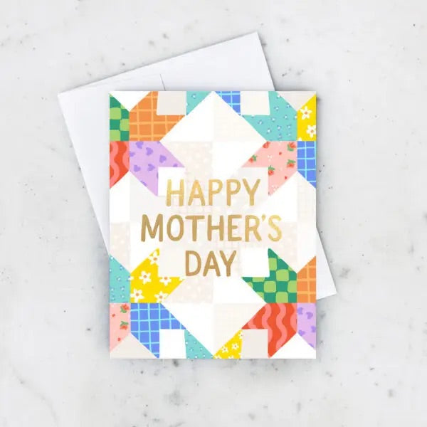 White greeting card with multicolor quilt pattern. Gold text “happy Mother’s Day” 