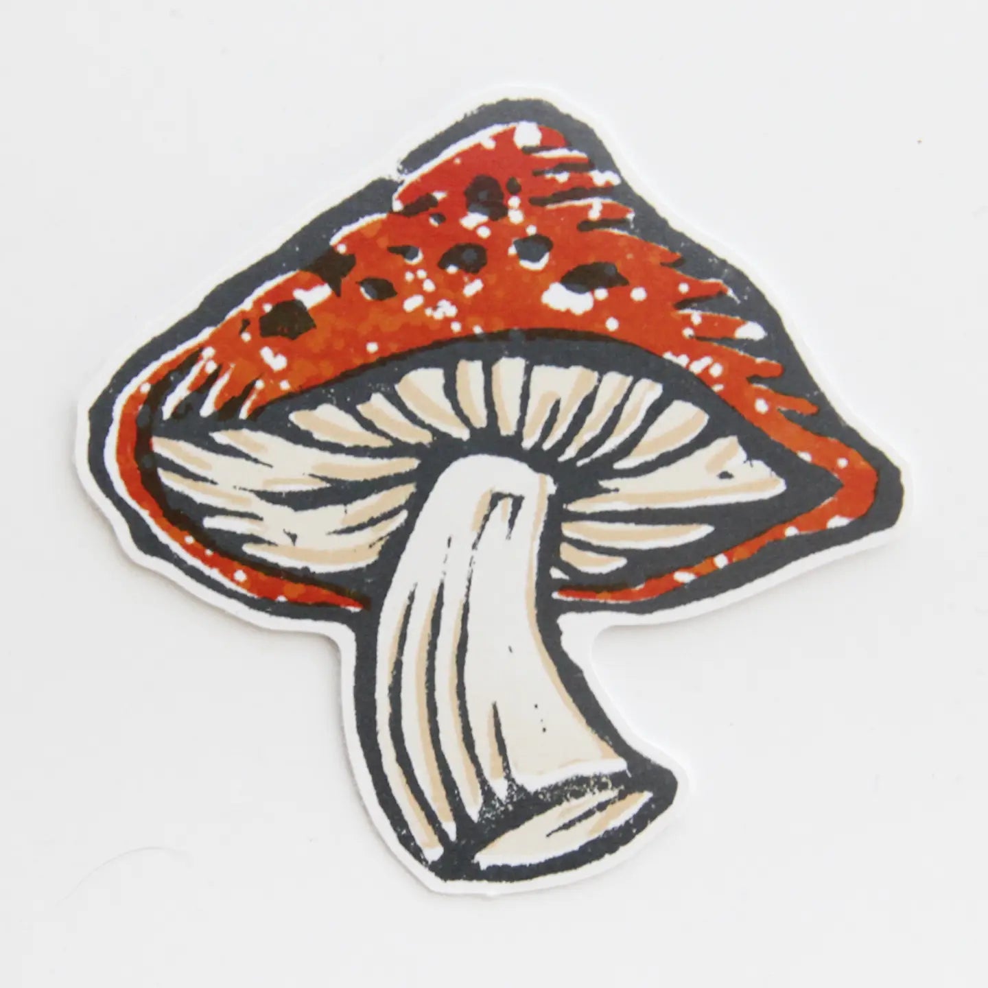 Mushroom-shaped sticker with red cap and white stem on a light gray background
