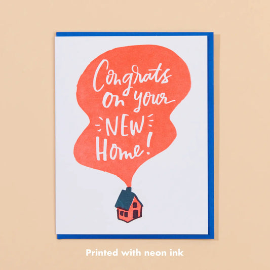 White card with illustration of an orange house. Orange blob coming from the chimney. Inside the blob is white text reading "congrats on your new home!" 