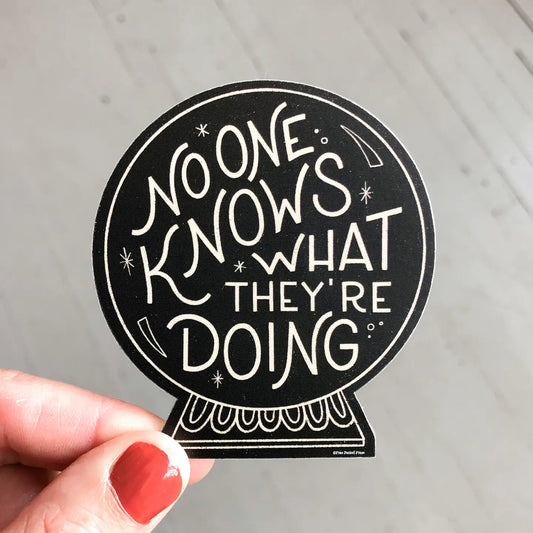 Black sticker. Sticker is shaped like a crystal ball. White text on sticker reads "no one knows what they're doing"