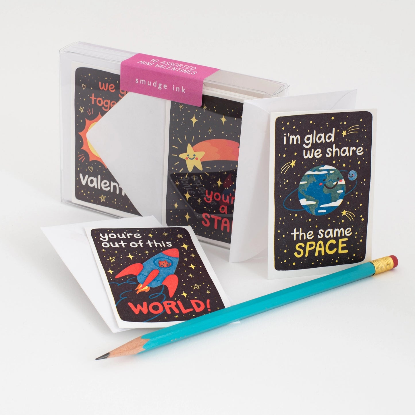 Box of space-themed valentines next to a blue pencil 