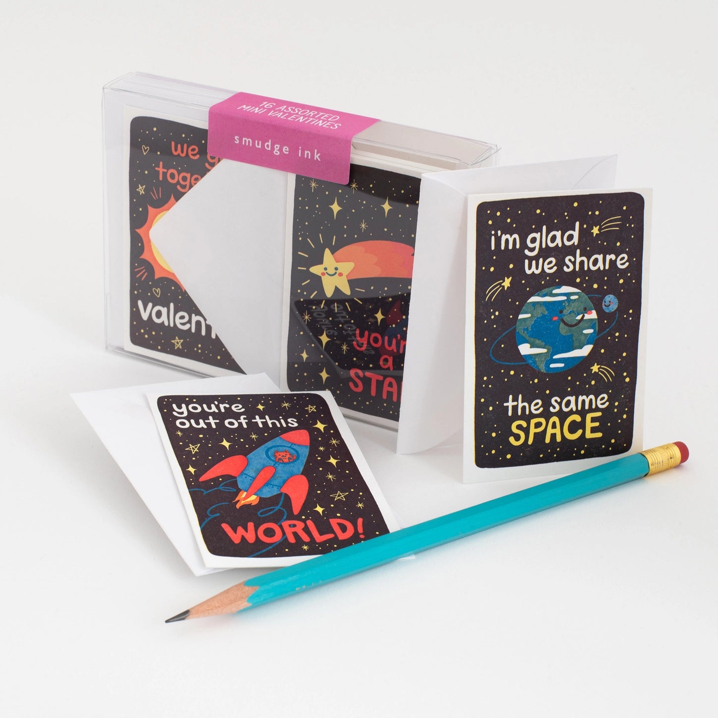 Box of space-themed valentines next to a blue pencil 