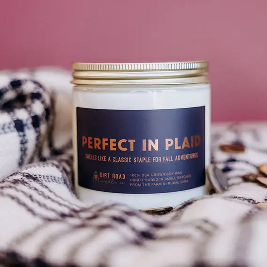 Candle with 'Perfect in Plaid' label on a plaid blanket