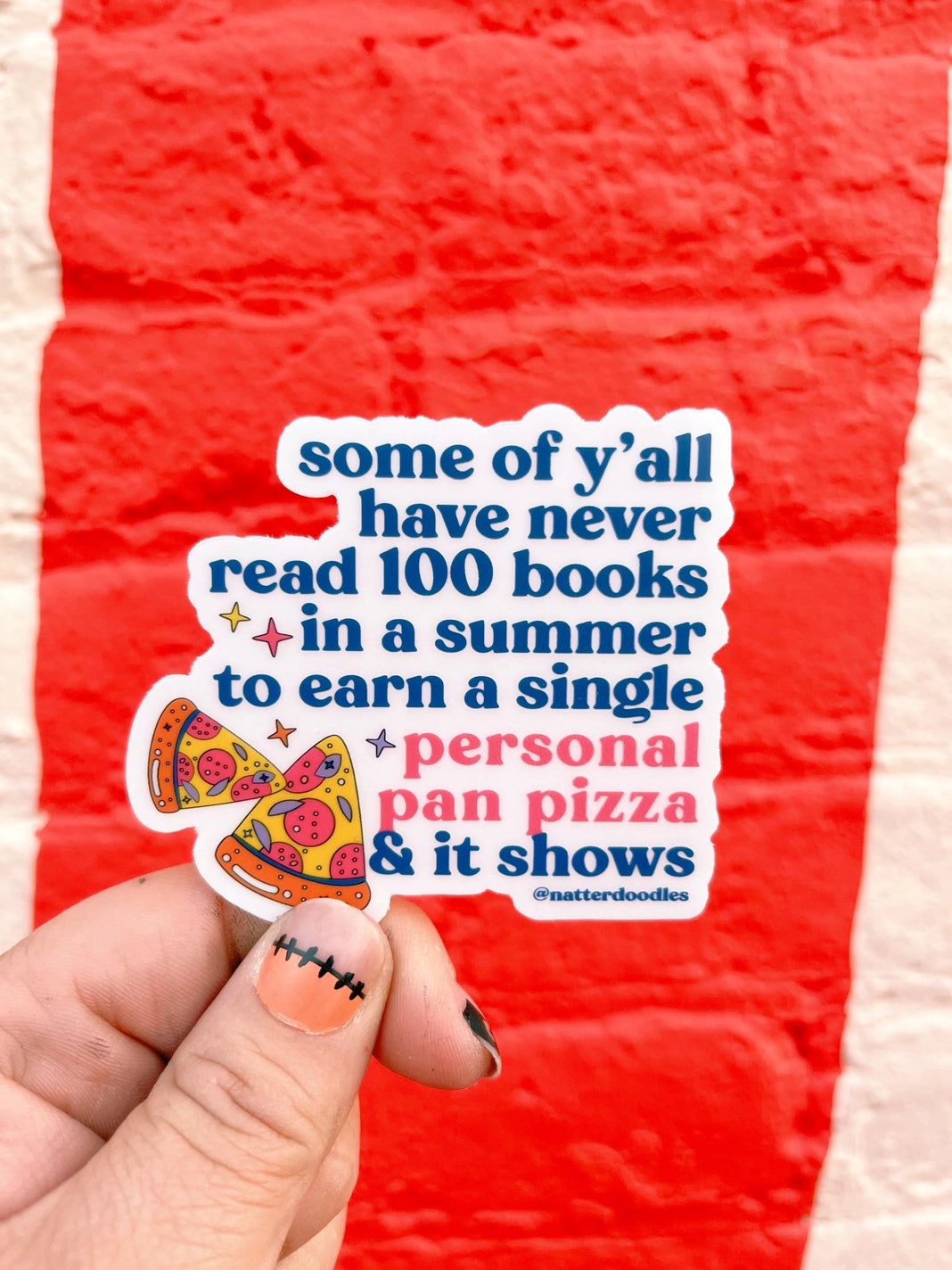 A die-cut sticker held against a red background. The text on the sticker includes a quote about summer reading and a personal pan pizza.