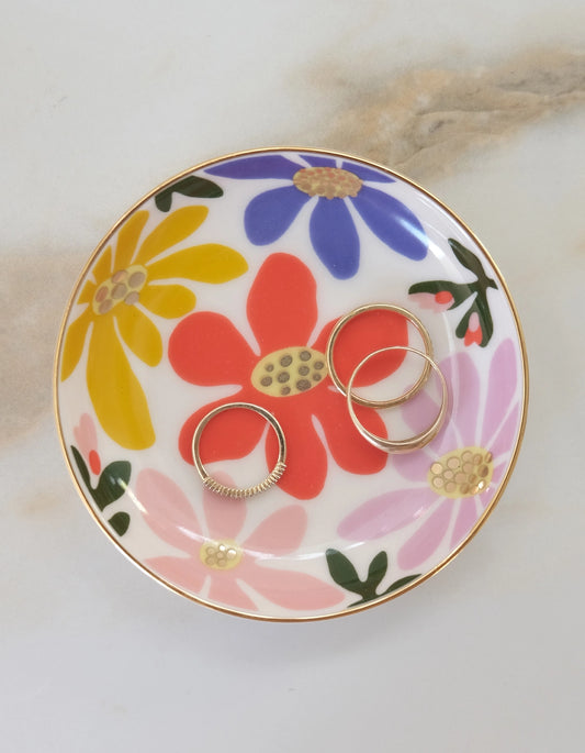 Floral-patterned trinket dish with gold rings on it 