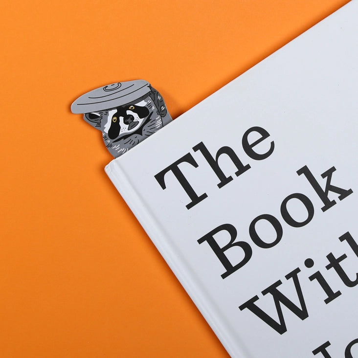 Raccoon bookmark sticking out of a closed book 