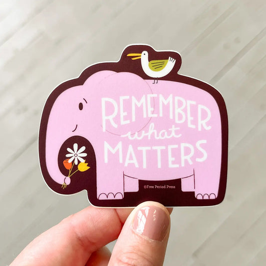 Die-cut pink sticker in an elephant shape. White text: remember what matters 