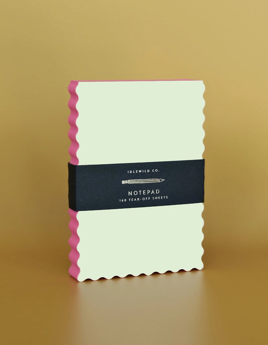 Yellow notepad with pink edge and black label on a beige background