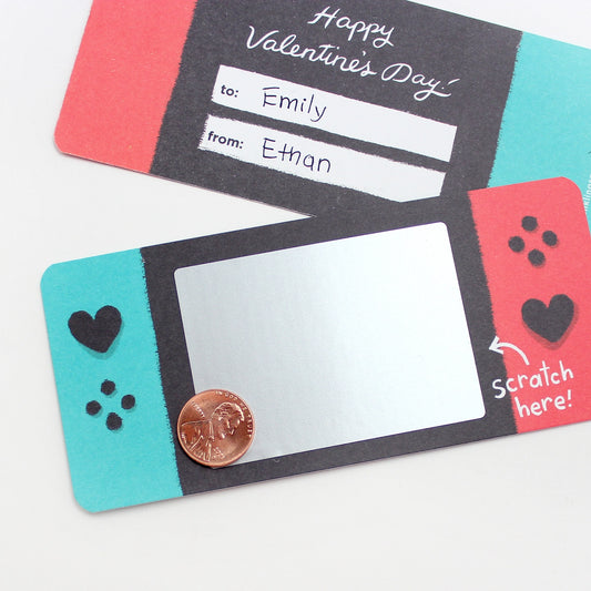 A set of video game-themed Valentine's Day scratch-off cards with a 'Happy Valentine's Day' message, personalization example, and a silver scratch-off sticker.