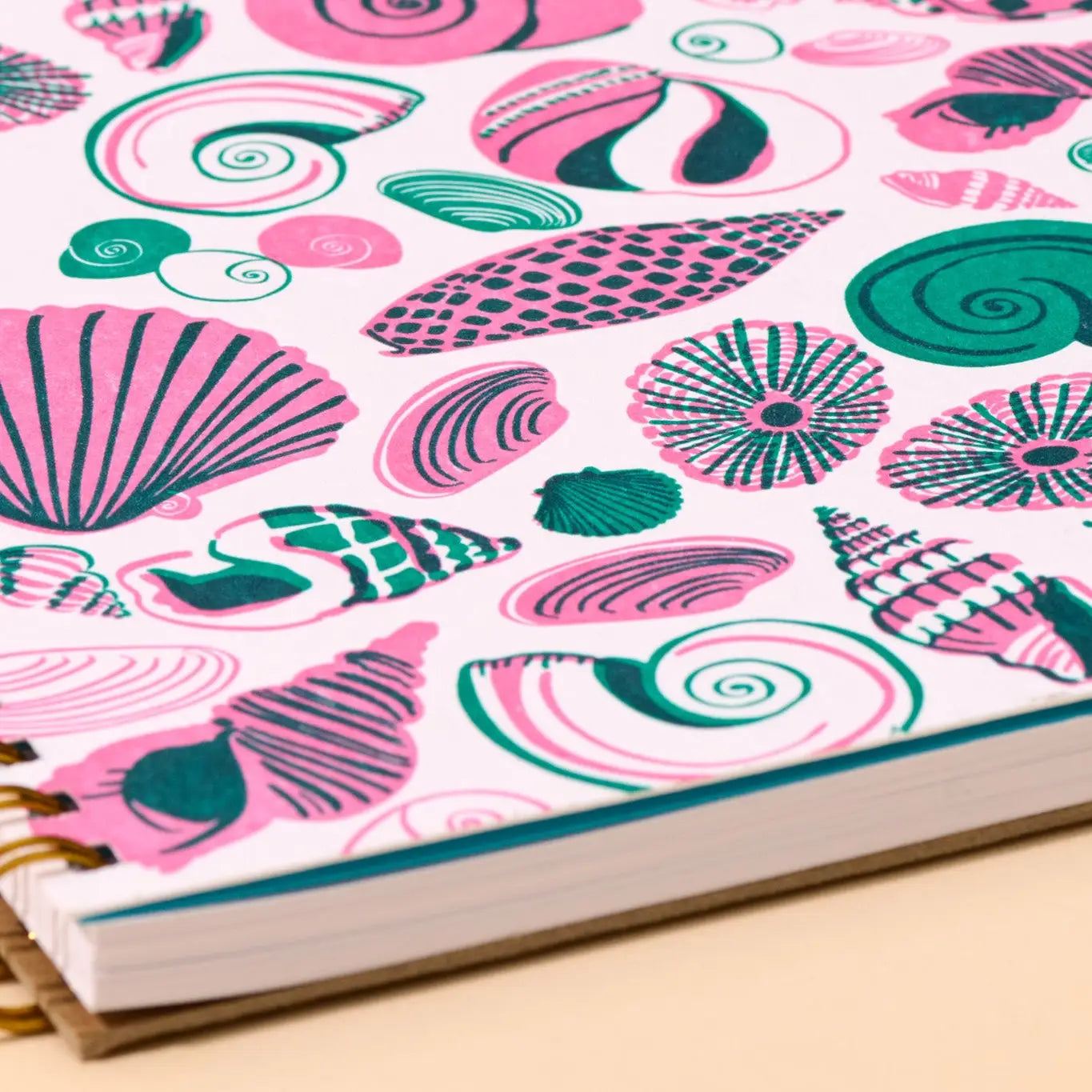 Notebook with pink and green shell pattern on a white background