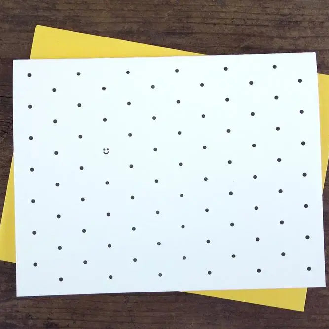 White card with black polkadot pattern and one black smiley face