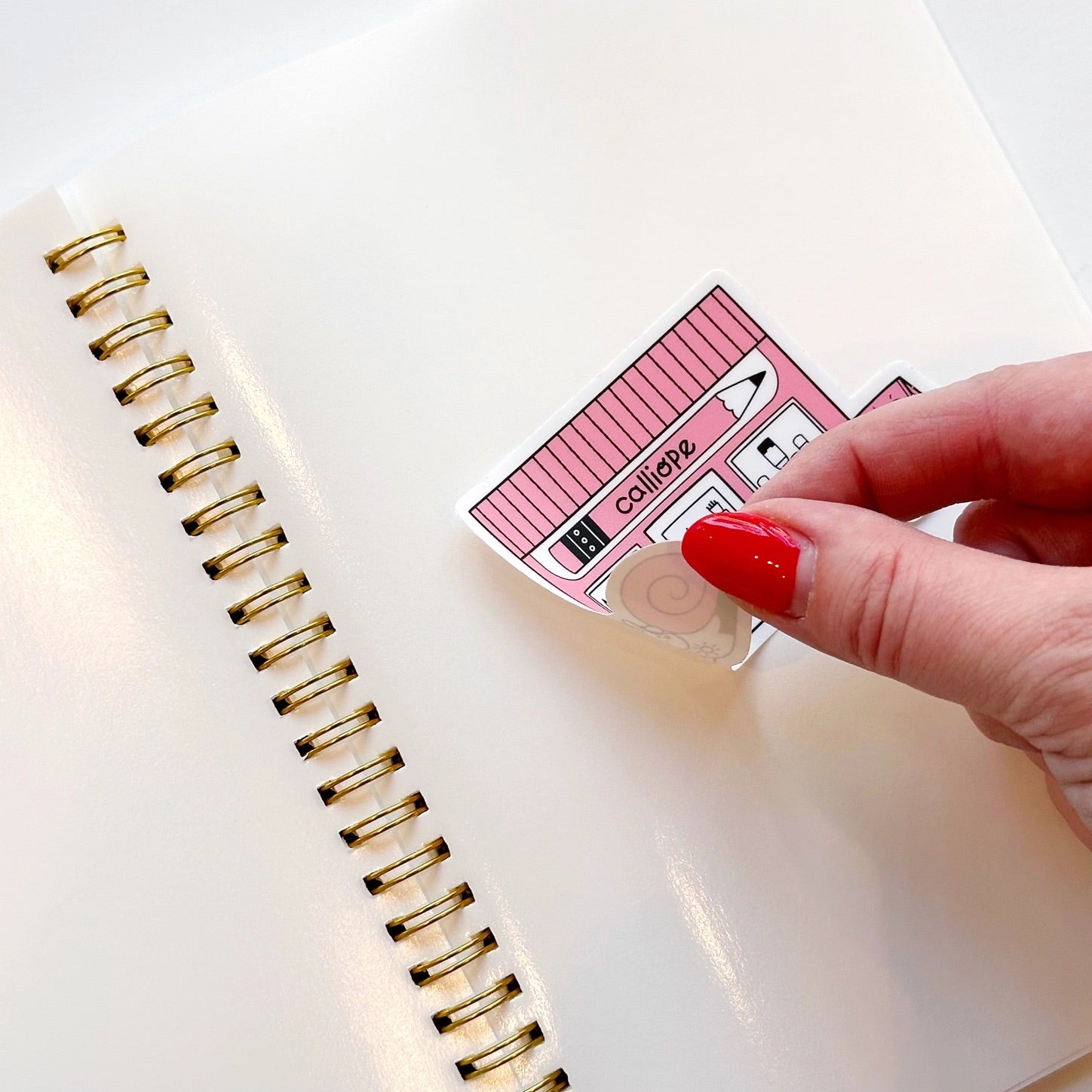 Front view of sticker book and a hand sticking a sticker to a page 