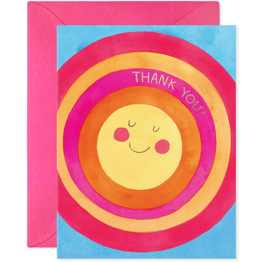 White greeting card with full color pink, red, and yellow smiling sun illustration. Gold text: thank you! 