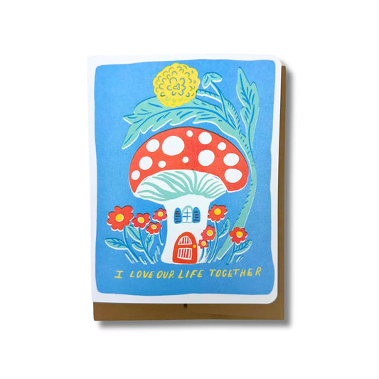 Greeting card with mushroom design and floral elements on a blue background. Yellow text: I love our life together 