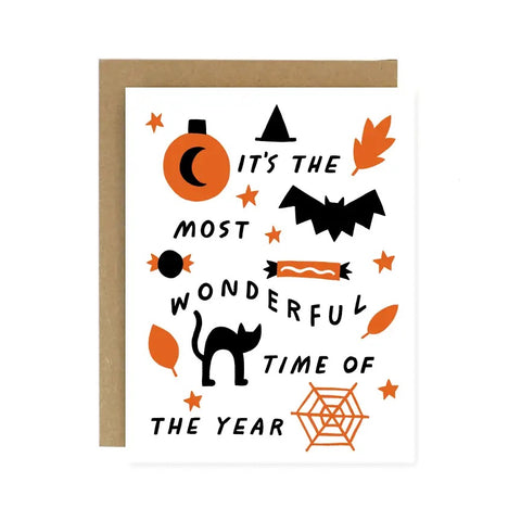 White card. Black text reads "it's the most wonderful time of the year." Black and orange ink drawings of a pumpkin, cat, spiderweb, leaves, candy, and a cobweb