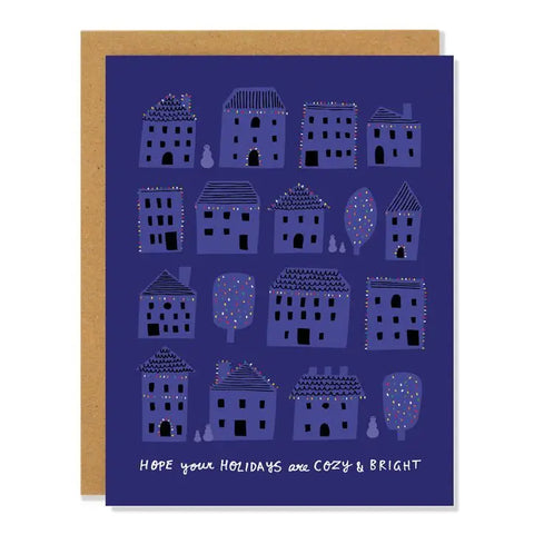 Blue/purple card with drawings of light blue/purple houses lit by holiday lights. White text reads "hope your holidays are cozy and bright." Inside of card is white. 