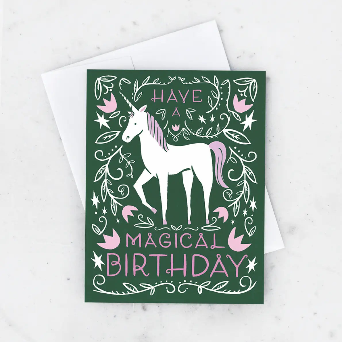White card with a green background and an illustration of a white unicorn with a pink mane. Pink text reads "have a magical birthday"