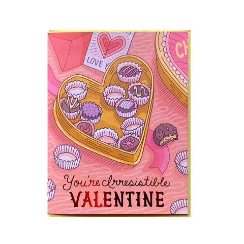 White card with pink background and a yellow heart-shaped box of chocolates. Some chocolates have been eaten.Shiny pink text reads "you're irresistible, valentine"