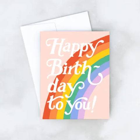 White card with pink background and a rainbow. White text reads "happy birth-day to you!"