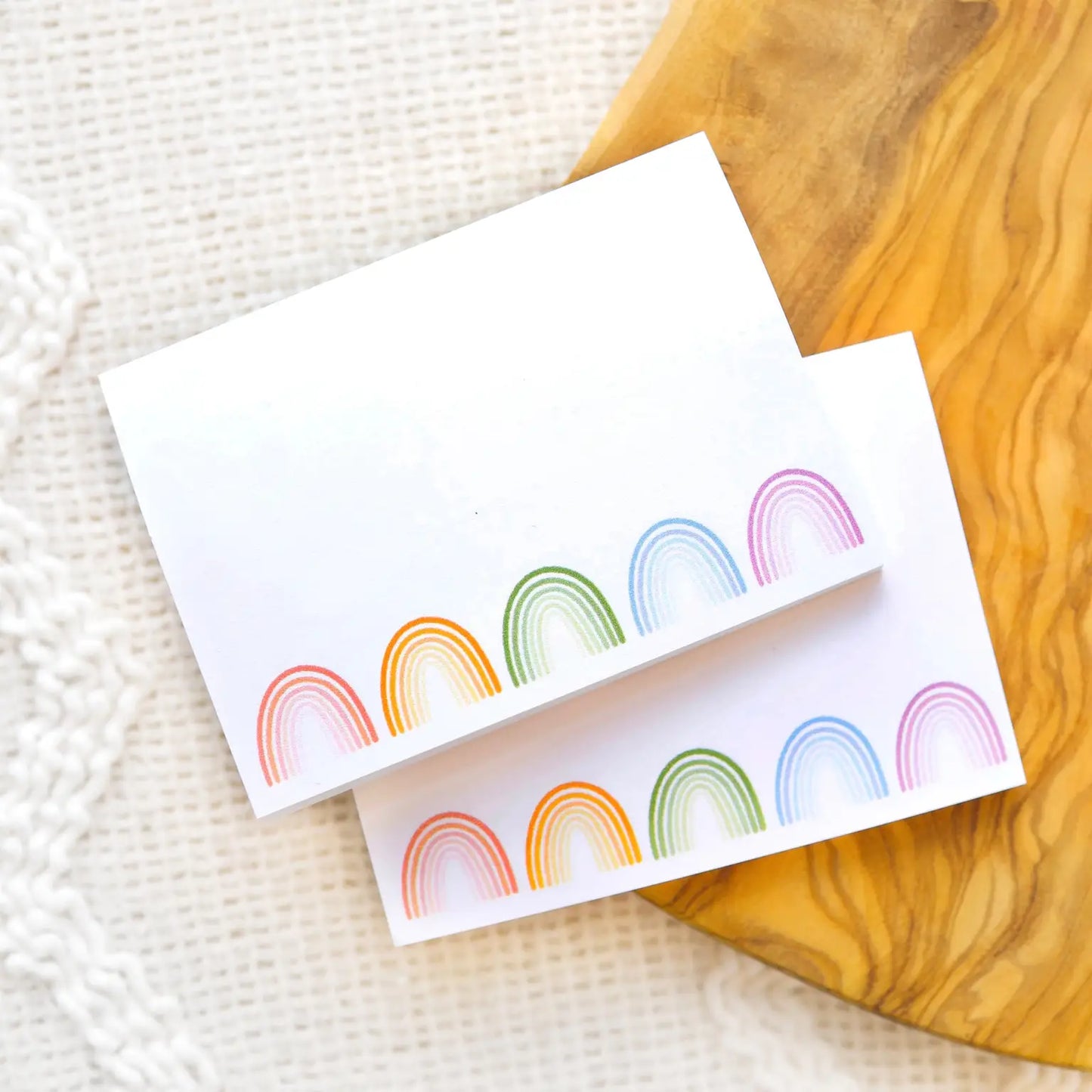 Pads of white sticky note paper with red, orange, green, blue, and purple rainbows on the bottom edge