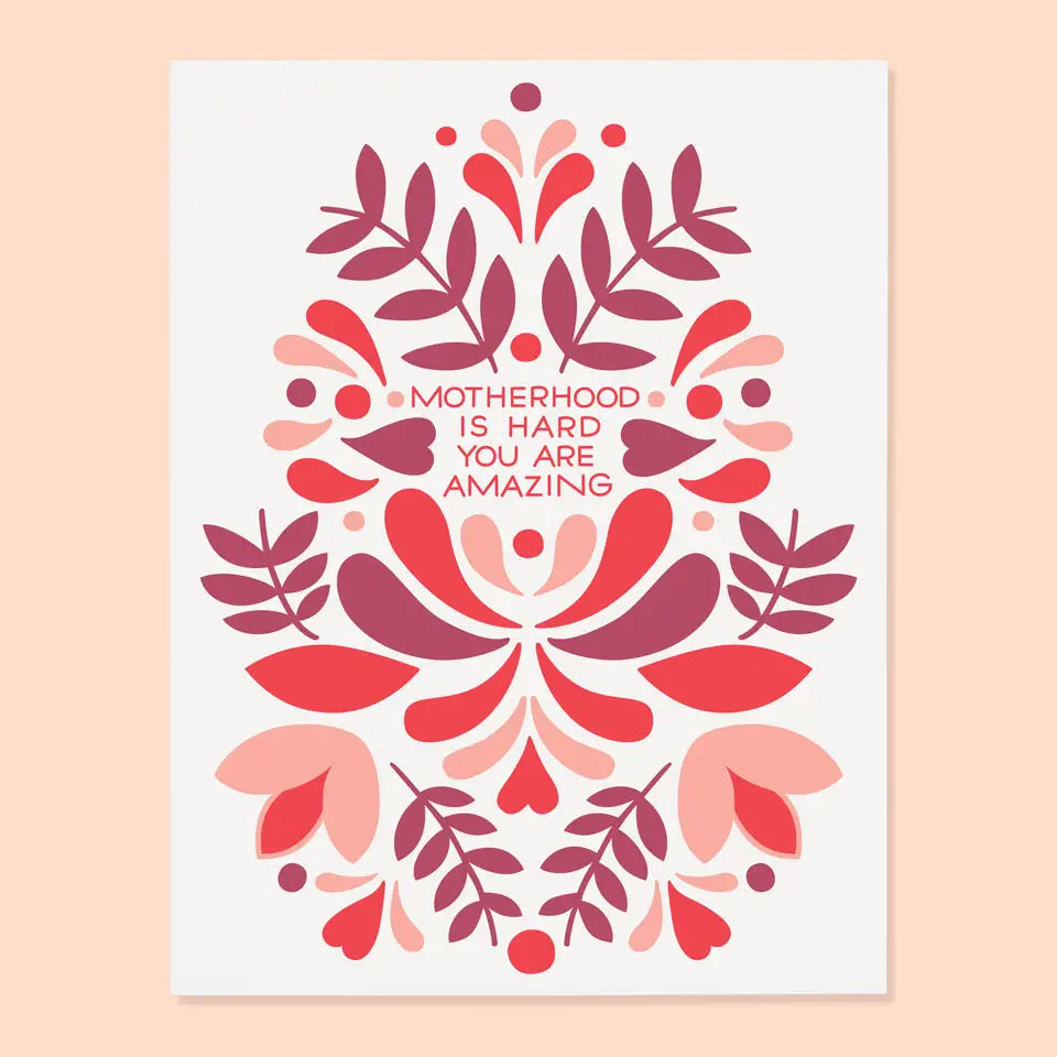 White card with pink, red, and maroon abstract floral shapes. Red text reads "motherhood is hard you are amazing" 