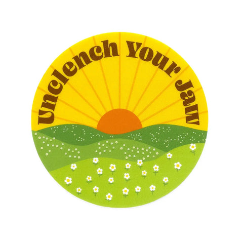 Round sticker, yellow sky, orange sun, green grass. Brown text says "unclench your jaw"