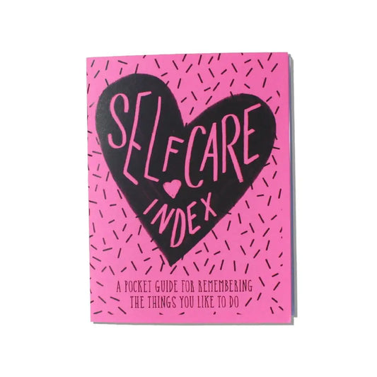 Front cover view of booklet. Pink cover with black heart in middle. Pink text reads "self care index. A pocket guide for remembering the things you like to do"