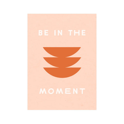 Pink background with abstract red shapes. White text reads "Be in the moment" 